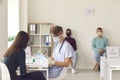 Doctor in face mask interviewing woman and filling out medical record before giving her vaccine Royalty Free Stock Photo