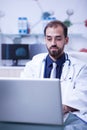 Young doctor thinking and working on his laptop in a private laboratory Royalty Free Stock Photo