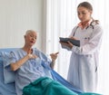 Young doctor visit the ward and talking to older female patient and note the information to chart for diagnosis Royalty Free Stock Photo