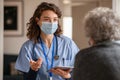 Young doctor visits senior woman with surgical mask Royalty Free Stock Photo