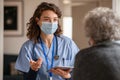 Young doctor visits senior woman with surgical mask