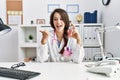 Young doctor woman holding electronic cigarette at medical clinic pointing thumb up to the side smiling happy with open mouth Royalty Free Stock Photo