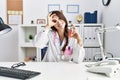 Young doctor woman holding electronic cigarette at medical clinic smiling happy doing ok sign with hand on eye looking through Royalty Free Stock Photo