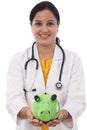 Young doctor woman holding a piggy bank Royalty Free Stock Photo