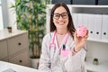 Young doctor woman holding piggy bank looking positive and happy standing and smiling with a confident smile showing teeth Royalty Free Stock Photo