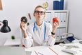 Young doctor woman holding red apple and donut at the clinic looking at the camera blowing a kiss being lovely and sexy Royalty Free Stock Photo