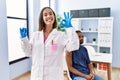 Young doctor woman holding vaccine showing syringe doing ok sign with fingers, smiling friendly gesturing excellent symbol Royalty Free Stock Photo