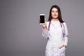 Young doctor woman pointing on cellphone screen on grey background