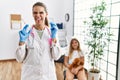 Young doctor woman putting vaccine to little girl sticking tongue out happy with funny expression Royalty Free Stock Photo