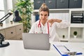 Young doctor woman wearing doctor uniform working using computer laptop with angry face, negative sign showing dislike with thumbs Royalty Free Stock Photo