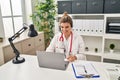 Young doctor woman wearing doctor uniform working using computer laptop looking positive and happy standing and smiling with a Royalty Free Stock Photo