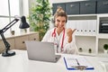 Young doctor woman wearing doctor uniform working using computer laptop pointing thumb up to the side smiling happy with open Royalty Free Stock Photo