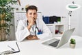 Young doctor working at the clinic using computer laptop looking stressed and nervous with hands on mouth biting nails Royalty Free Stock Photo