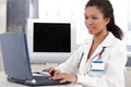 Young doctor working on laptop computer smiling Royalty Free Stock Photo