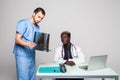 Young doctors discussing diagnosis in bright office. Two doctors disscusing xray at office table isolated on white background Royalty Free Stock Photo