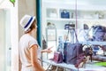 Young doubting girl looking at shop window with shoes and bags in Shopping Mall. Shopper. Sales. Shopping Center. Space for text. Royalty Free Stock Photo