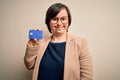 Young down syndrome business woman holding credit card as customer payment with a happy face standing and smiling with a confident Royalty Free Stock Photo