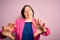 Young down syndrome business woman over pink background afraid and terrified with fear expression stop gesture with hands, Royalty Free Stock Photo