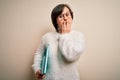 Young down syndrome student woman reading a book from library over isolated background cover mouth with hand shocked with shame Royalty Free Stock Photo