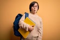 Young down syndrome student woman wearing glasses and school back holding books from library scared in shock with a surprise face, Royalty Free Stock Photo