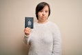 Young down syndrome tourist woman holding canada passport as trip document with a confident expression on smart face thinking