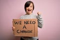 Young down syndrome woman holding protest banner we need a change from political problems screaming proud and celebrating victory