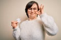 Young down syndrome woman holding puzzle piece as problem solution and cooperation union doing ok sign with fingers, excellent