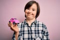 Young down syndrome woman holding small car as driving license insurance over pink background with a happy face standing and Royalty Free Stock Photo
