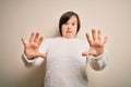 Young down syndrome woman standing over isolated background afraid and terrified with fear expression stop gesture with hands, Royalty Free Stock Photo