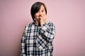 Young down syndrome woman wearing casual shirt over pink background looking stressed and nervous with hands on mouth biting nails Royalty Free Stock Photo