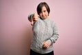 Young down syndrome woman wearing casual sweater over isolated background looking unhappy and angry showing rejection and negative Royalty Free Stock Photo