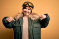 Young down syndrome woman wearing ski coat and glasses for winter weather looking confident with smile on face, pointing oneself Royalty Free Stock Photo