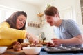 Young Downs Syndrome Couple Decorating Homemade Cupcakes With Icing In Kitchen At Home