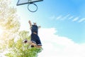 Young dreadlocks player dunking in urban city basketball court with back sun light - Strong athlete performing slam dunk at