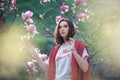 Young dreamed woman with blooming magnolia tree. Pretty fashion girl near pink flowers