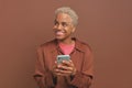 Young dreamer African American woman with mobile phone smiling and looking away Royalty Free Stock Photo