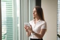 Young dreamy beautiful businesswoman looking through window whil Royalty Free Stock Photo