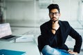 Young dreamy indian businessman in suit thinking of business vision outlook planning future project idea at work with laptop, succ Royalty Free Stock Photo