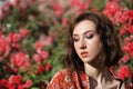 Young dreamy woman with red roses. Outdoor portrait of a romantic girl with hard sunlight. Space for text