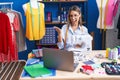 Young dressmaker woman using sewing machine celebrating achievement with happy smile and winner expression with raised hand Royalty Free Stock Photo