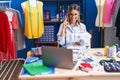 Young dressmaker woman using sewing machine smiling with an idea or question pointing finger with happy face, number one Royalty Free Stock Photo