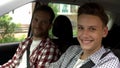 Young driver and his father smiling into camera, teen getting driving license