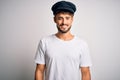 Young driver man with beard wearing hat standing over isolated white background with a happy and cool smile on face