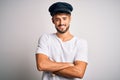 Young driver man with beard wearing hat standing over isolated white background happy face smiling with crossed arms looking at Royalty Free Stock Photo