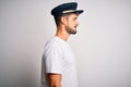 Young driver man with beard wearing hat standing over isolated white background looking to side, relax profile pose with natural