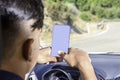 Young driver, using smartphone, on the road in the car Royalty Free Stock Photo