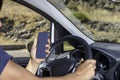 Young driver, using smartphone, on the road in the car Royalty Free Stock Photo