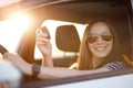 Young driver woman hold key of rented or new car