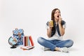 Young drowsy woman student holding paper cup with coffee or tea yawning want sleep sitting near globe, backpack, school