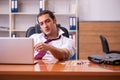 Young drug addicted male employee working in the office Royalty Free Stock Photo